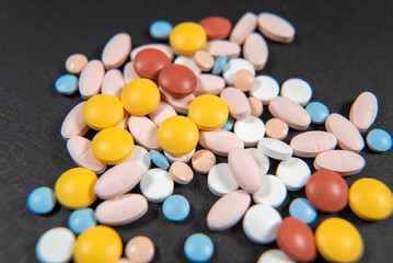 Many assorted pharmaceutical pills, tablets and capsules scattered on the black background. health care