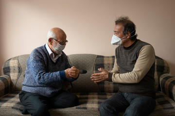 Senior man wearing mask shows an elderly man how to wash hands properly