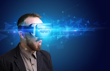 Businessman looking through Virtual Reality glasses with INTELLECTUAL PROPERTY inscription, cyber security concept