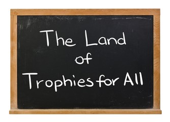 Obraz premium The land of trophies for all written in white chalk on a black chalkboard isolated on white
