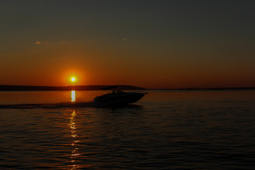 The boat floats on the sea at sunset