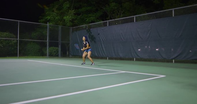 Woman playing tennis at night