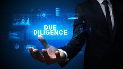 Hand of Businessman holding DUE DILIGENCE inscription, business success concept