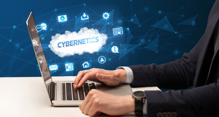 Businessman working on laptop with CYBERNETICS inscription, modern technology concept