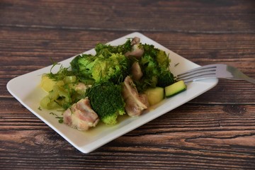 stewed vegetables and pieces of chicken on a white plate on a wooden table
