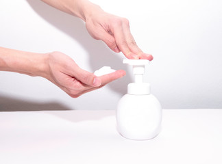 The hand is pressing the foam soap bottle