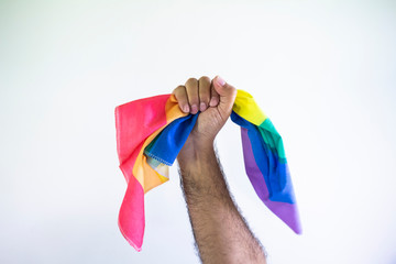 A man's hand with a clenched fist holding a flag of the LGBT community. Concept of fight for...