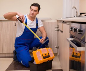 Young repairman working at the kitchen