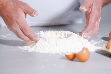 Male hands working with flour and eggs