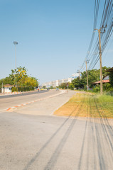 The road outside the city has low buildings. Light poles and trees on both sides