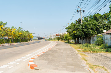 The road outside the city has low buildings. Light poles and trees on both sides