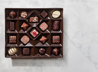 Box of chocolates on light background. Flat lay, top view.