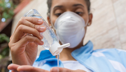 COVID-19 Woman wearing face mask and putting alcohol gel on.