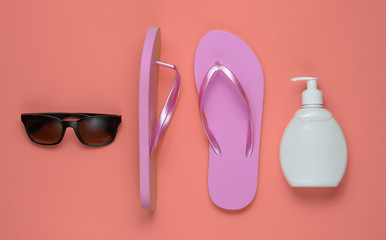 Beach accessories. Fashionable beach pink flip flops, sunblock bottle, sunglasses on pink paper...