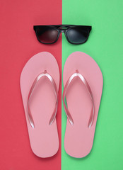 Summer still life. Beach accessories. Fashionable beach pink flip flops, sunglasses on pink green ...
