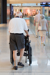 Older people go to the mall. A buyer a pensioner with wheelchair moves around a large store