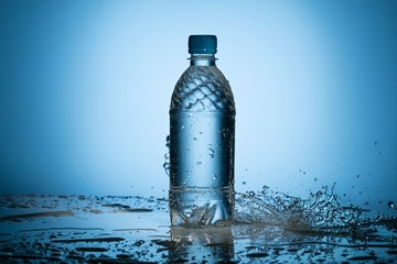 Clear water splashing near translucent plastic bottle