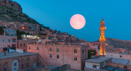 Sehidiye mosque with ful moon - Mardin old town at dusk. Historical beige colored limestone rock...