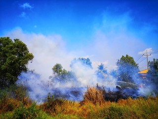 Fireman using water and extinguisher to fighting with fire flame in an emergency situation.,There is dirty smoke floating over the area.