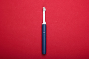 Modern electric toothbrush on red background. Top view. Teeth care. Minimalism