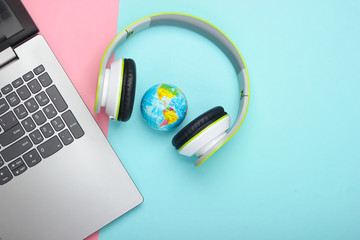 Global network, internet. World music song. Laptop, stereo headphones and globe on pink blue pastel...