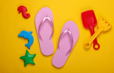 Children's beach toys, flip flops on a yellow background. Beach Vacation Concept. Top view