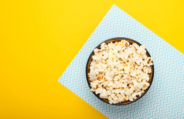 Bowl of popcorn on yellow blue pastel background. Leisure and entertainment concept. Top view