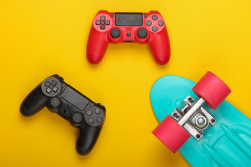 Gamepads with cruiser board on a yellow background. Childhood concept, summer fun, entertainment. Top view. Flat lay