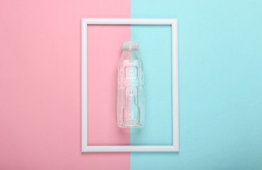 Plastic bottle of water on pink blue pastel background with white frame. Studio shot. Creative flat lay. Top view. Minimalism