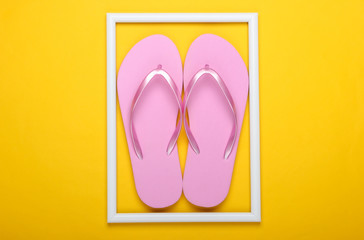 Flip flops on yellow background with white frame. Studio shot. Creative beach resort flat lay. Top view. Minimalism