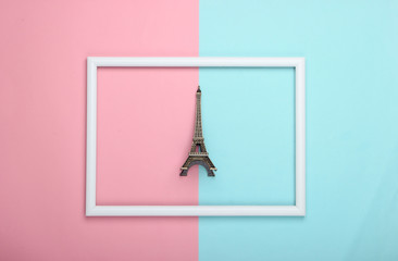 Travel concept. figurine of eiffel tower in a white frame on a blue-pink pastel background