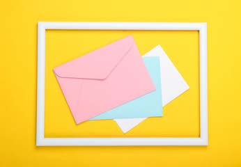 Envelopes in a white frame on a yellow background. Top view. Flat lay