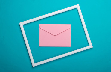 Envelope in a white frame on blue background. Top view. Flat lay