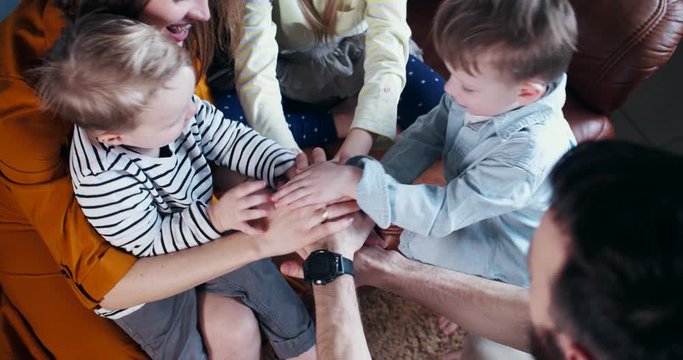 Top view happy Caucasian mom and dad with three children joining hands, cheerful family teamwork concept slow motion.