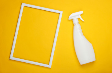 Bottle of spray for washing windows on yellow background with a white frame. Top view. Minimalism