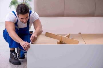 Young male contractor installing furniture at home
