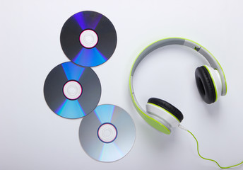 Stylish wired stereo headphones and cd discs on white background. Music lover. Retro 90s. Top view.