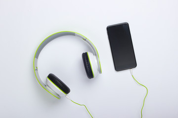 Stylish wired stereo headphones with smartphone on white background. Music lover. Top view. Minimalism