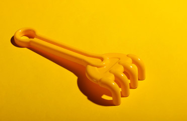 Children's toy rake for the sandbox on a yellow background