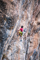 Naklejka na ściany i meble ?limber overcomes a difficult climbing route on a natural terrain.