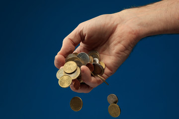 The concept of falling revenue/income. Various coins from around the world held in hand. Coins...