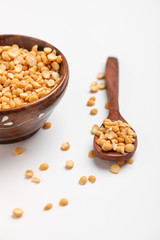 Dried chickpea lentils in wooden bowl and spoon on white background , Split Chickpea Also Know as Chana Dal