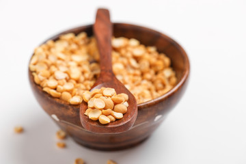 Dried chickpea lentils in wooden bowl and spoon on white background , Split Chickpea Also Know as Chana Dal