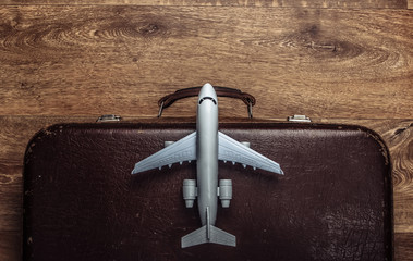 Travel concept. Old luggage and airplane figurine on wooden floor. Flight voyage, trip, journey. Flat lay composition. Top view