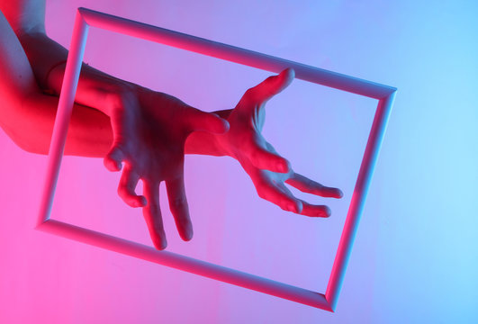 Creative art. Female hands through a soaring frame with neon holographic light. Gradient glow. Pop art. 80s