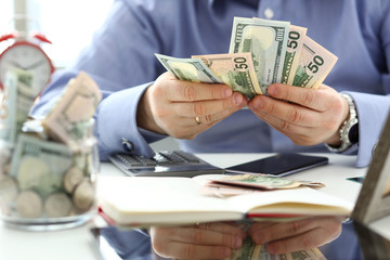 Fototapeta premium Male arms counting big amount of US currency at worktable closeup