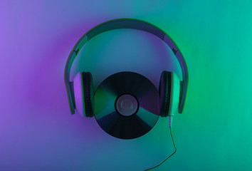 Stereo headphones with cd disc. Neon purple green light. Gradient glow. 80s. Top view