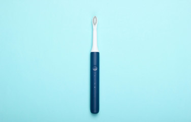 Modern electric toothbrush on blue pastel background. Top view. Teeth care. Minimalism