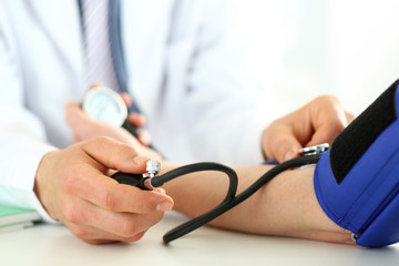 Close-up of specialist's hands performing blood pressure check procedure with professional stethoscope and special devices. Patient worried about state of health. Medical treatment concept
