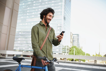 Handsome young man with beard and cycle using smartphone to read text message